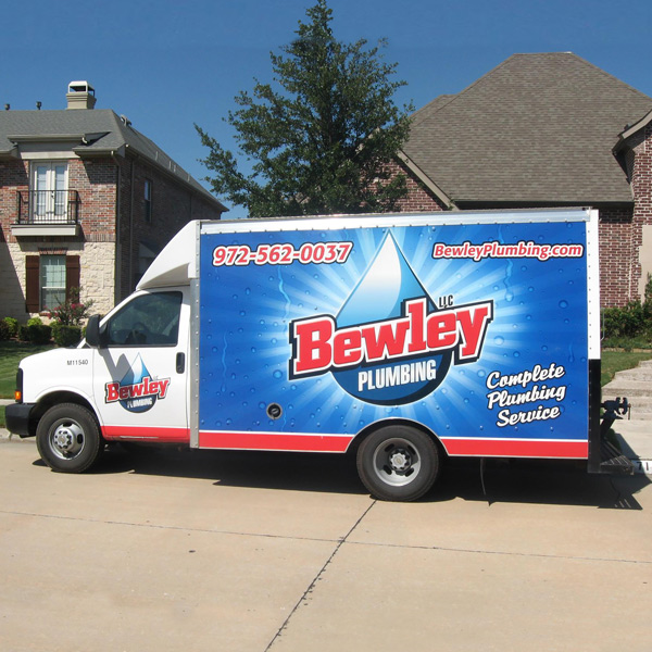 Bewley Plumbing box truck in front of a residential street with beautiful homes behind it