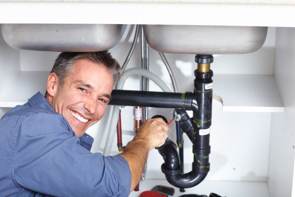 plumber smiling while working on a sink