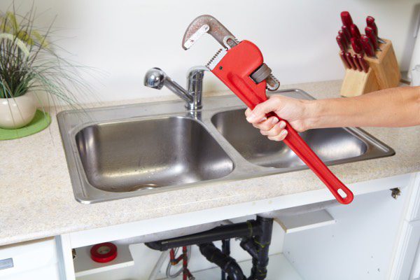 A plumber working on a clogged kitchen sink drain.